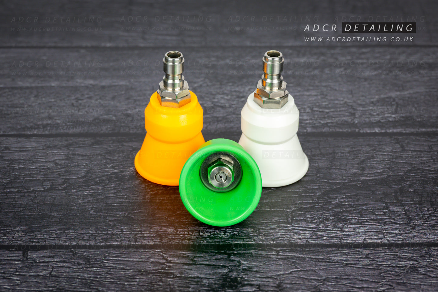 Three premium quick release stainless steel pressure washer spray nozzles in yellow, green, and white on a dark wooden surface with 'ADCR Detailing' branding.